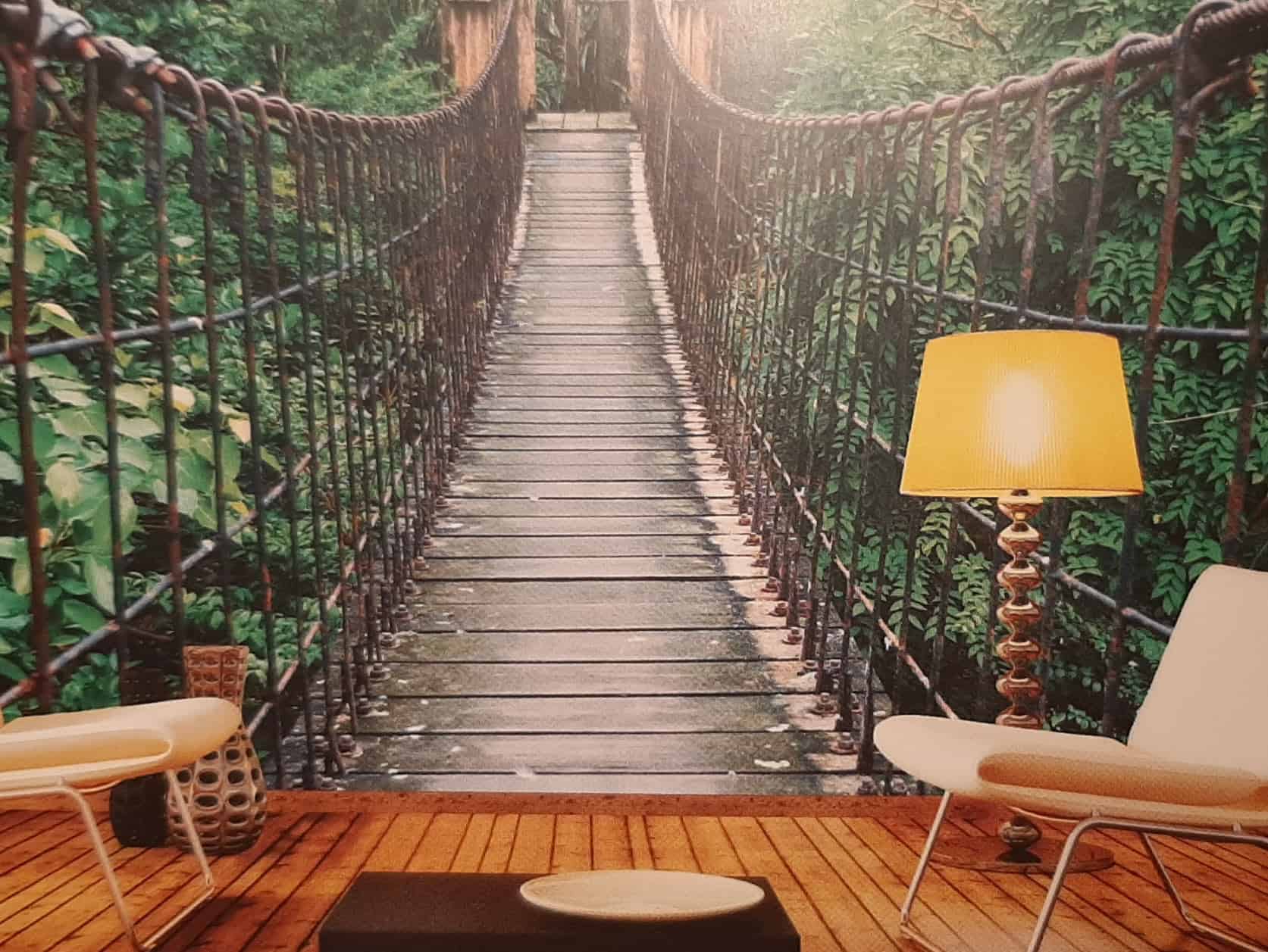 Esempio di fotomurale di ponte sospeso di legno e corde nella giungla applicato a una parete del soggiorno